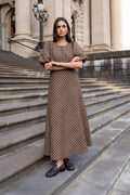 Woman in a patterned dress standing on stone steps in front of a classical building.