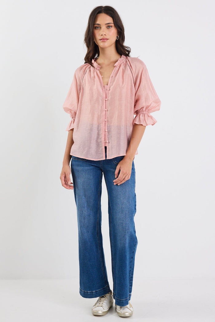 Woman wearing a pink blouse and blue jeans on a white background