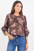 Woman wearing a floral blouse with long sleeves and blue jeans on a white background