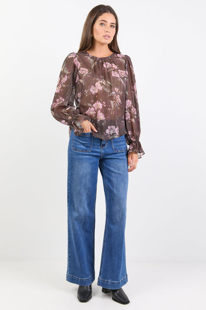 Woman wearing a floral blouse and blue jeans on a white background
