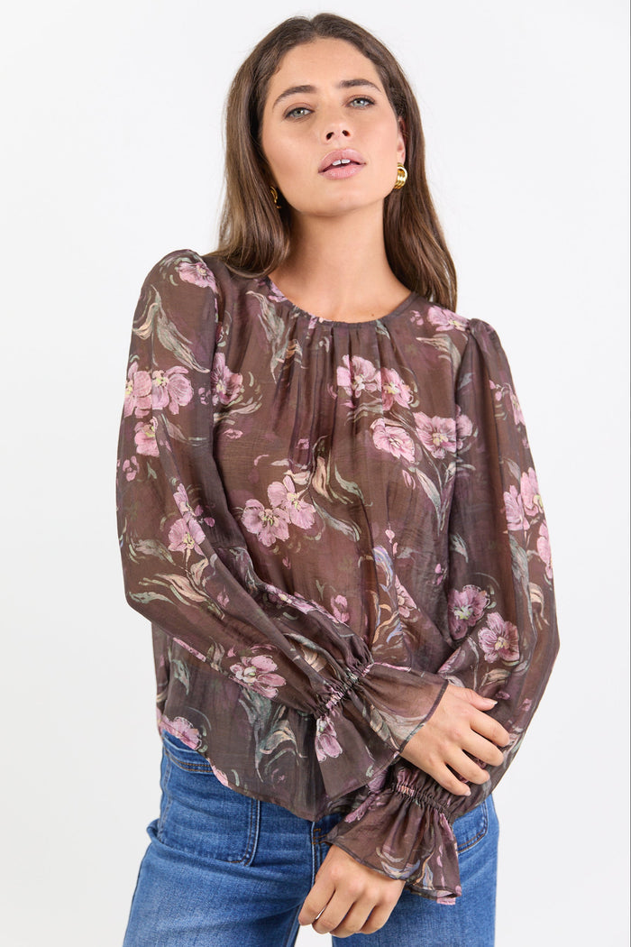 Woman wearing a floral blouse with long sleeves on a white background