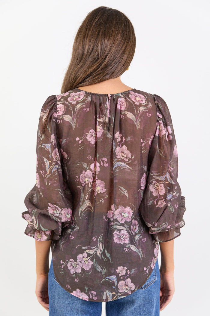 Woman wearing a floral blouse with long sleeves on a white background