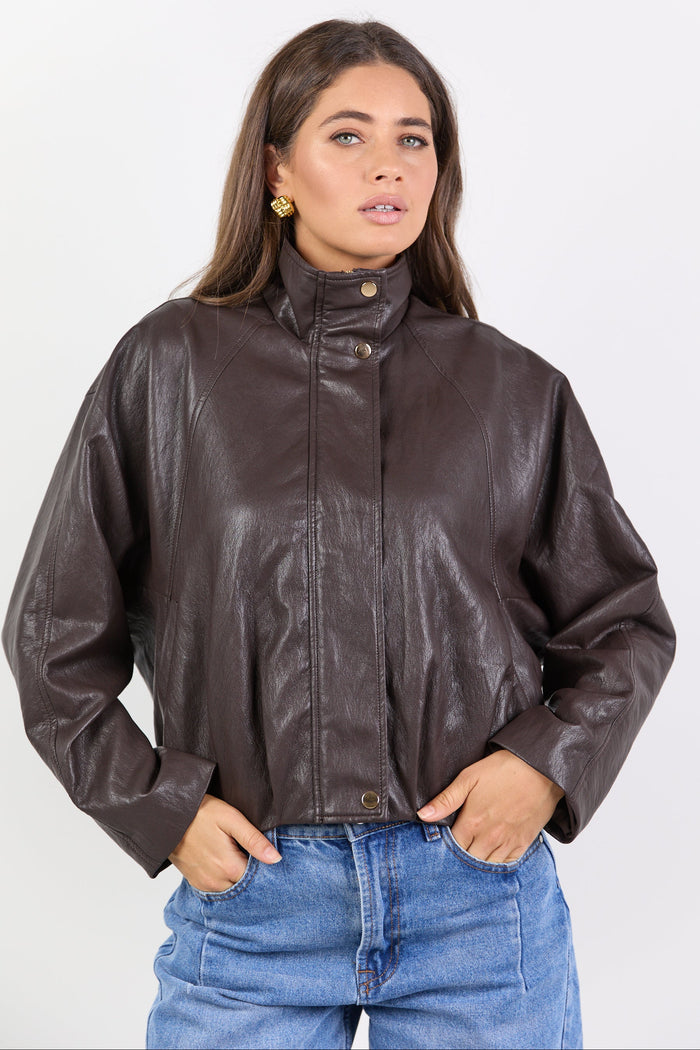 Woman wearing a brown leather jacket and blue jeans on a white background