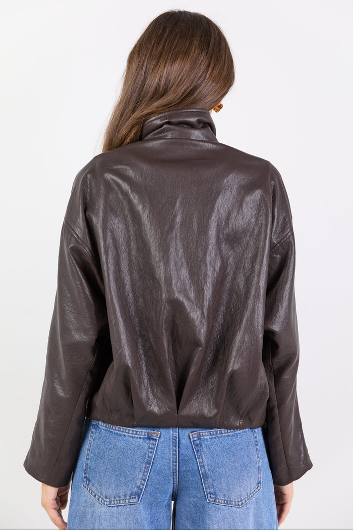 Person wearing a brown leather jacket and blue jeans on a white background
