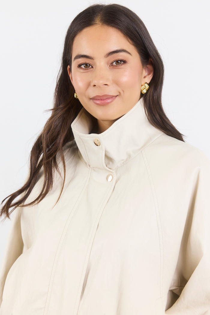 Woman wearing a cream-colored coat against a white background