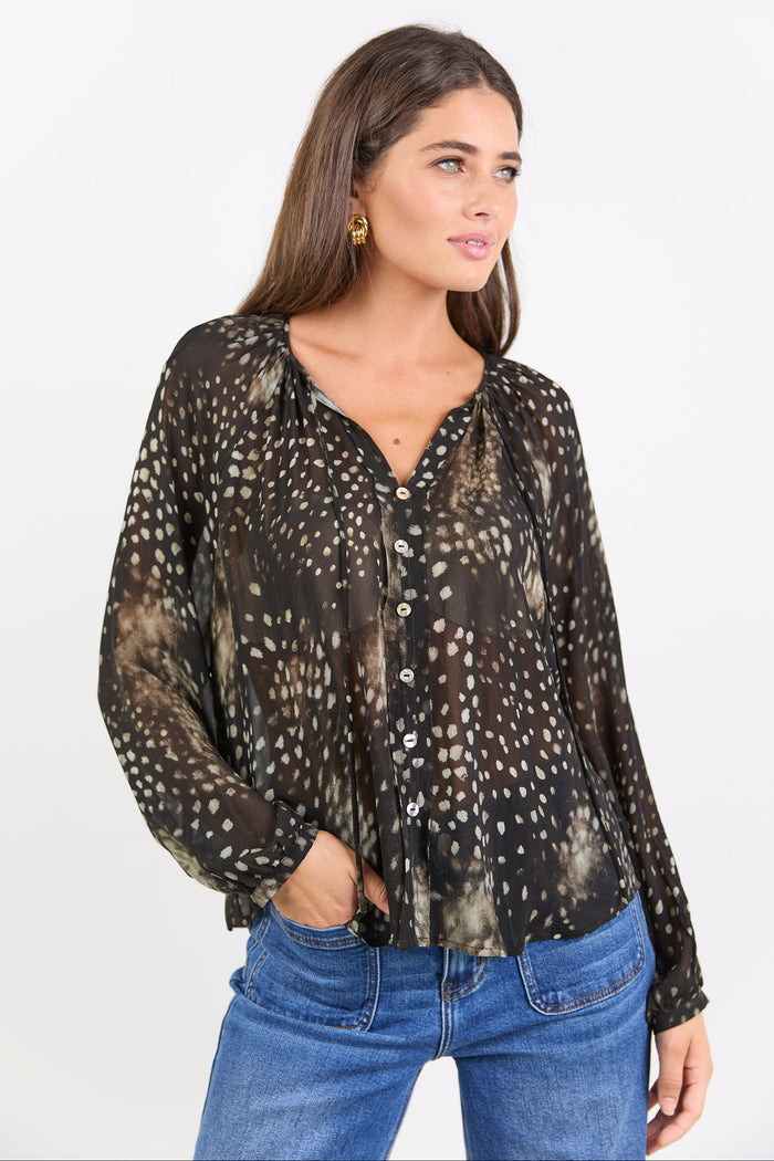 Woman wearing a patterned blouse and blue jeans on a white background
