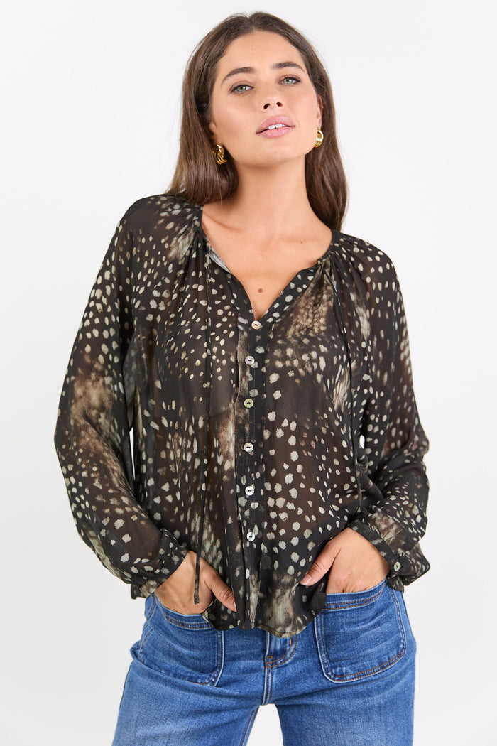 Woman wearing a patterned blouse and jeans on a white background