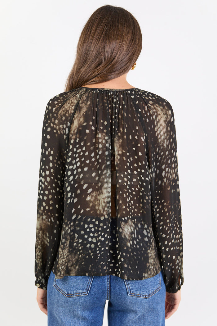 Woman wearing a blouse with animal print and blue jeans on a white background