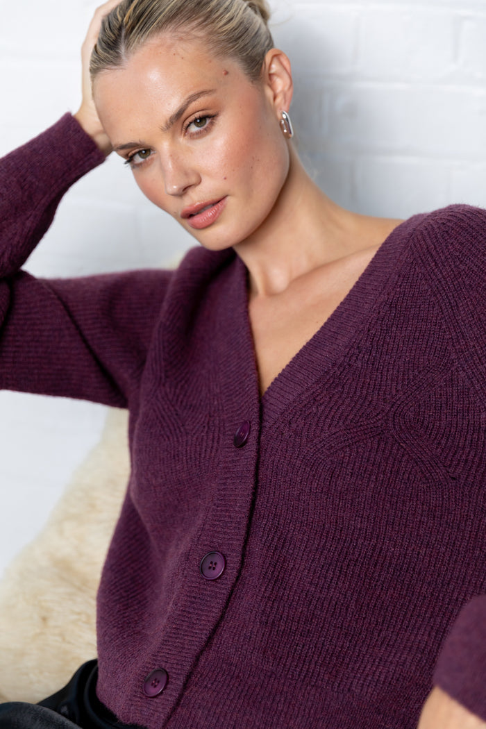 Woman wearing a purple cardigan against a neutral background