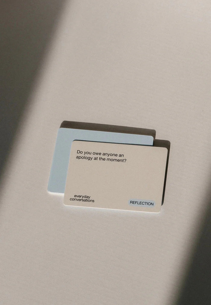Card with text 'Do you owe anyone an apology at the moment?' on a reflective surface.