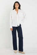 Woman wearing a white blouse and dark blue jeans on a white background
