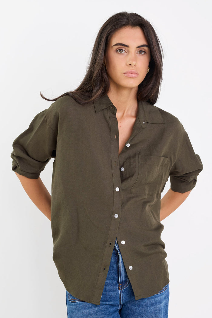 Woman wearing an olive green shirt and blue jeans on a white background