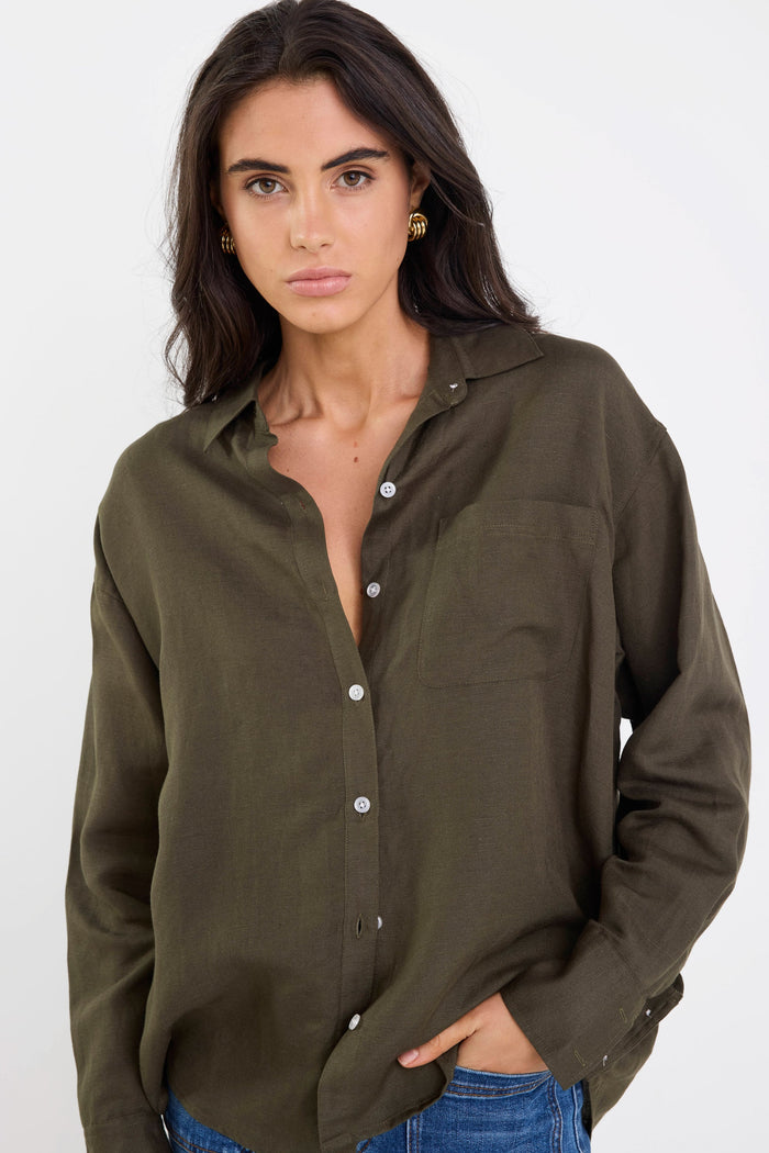 Woman wearing an olive green button-up shirt on a white background