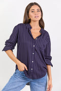 Women wearing navy shirt with white stripes and blue jeans on white background.