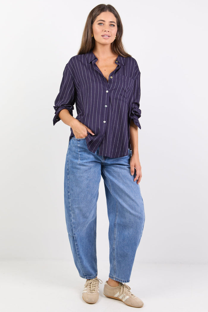 Women wearing navy shirt with white stripes and blue jeans on white background.