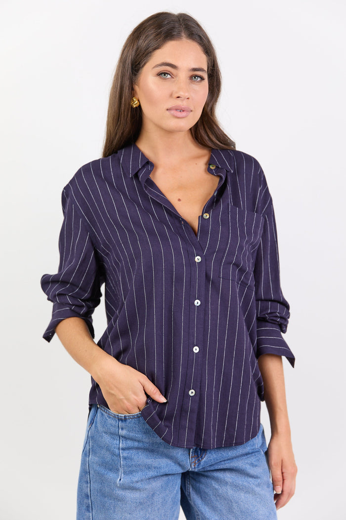 Women wearing navy shirt with white stripes and jeans on white background.