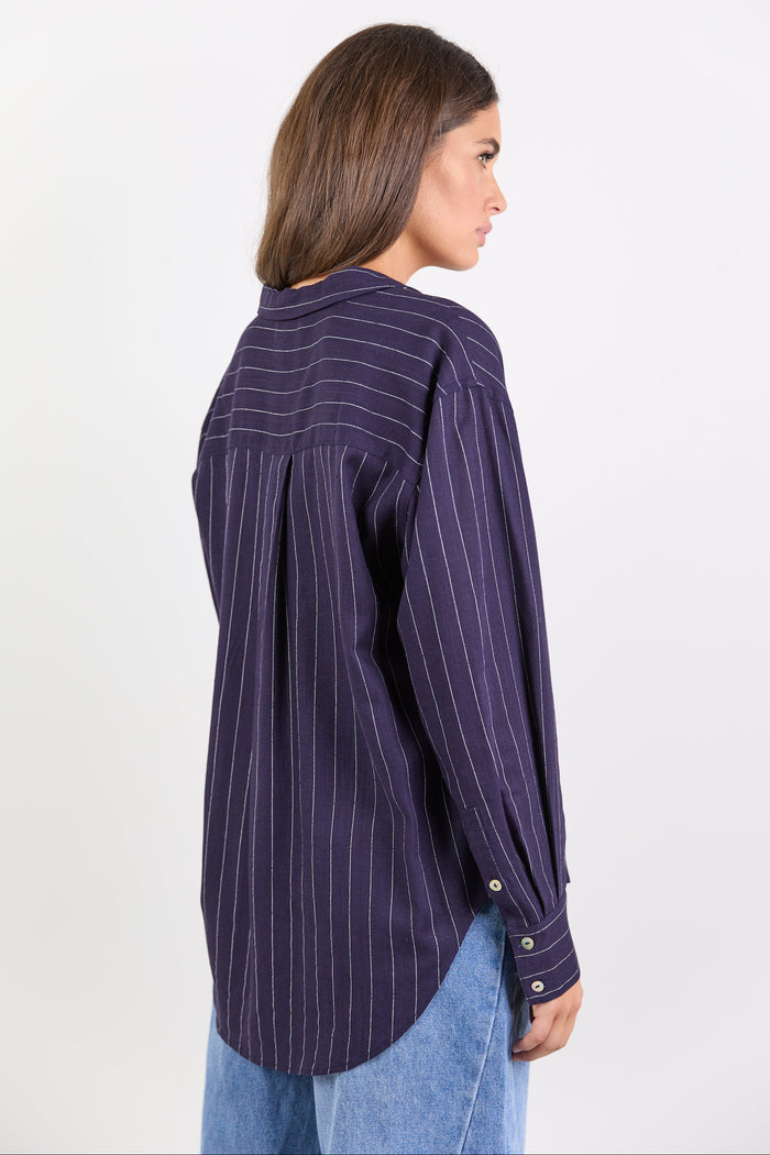 Women wearing navy shirt with white stripes and blue jeans on white background.