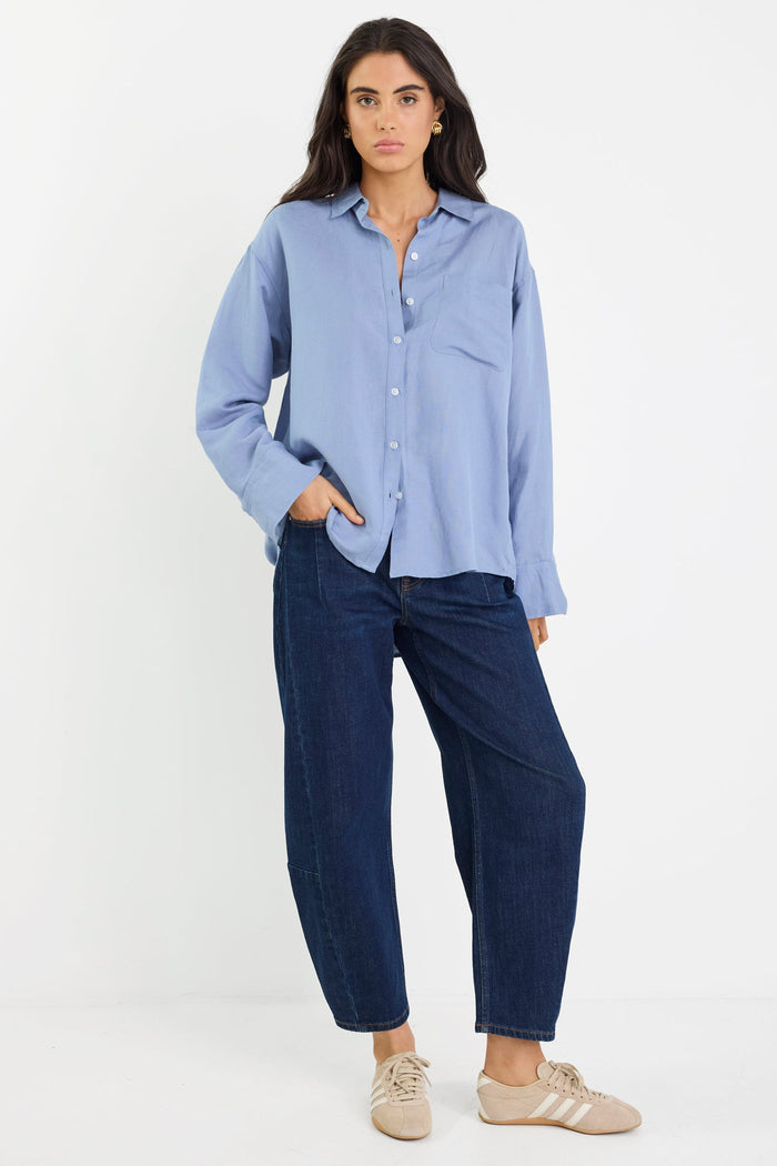 Woman wearing a light blue shirt and dark blue pants on a white background