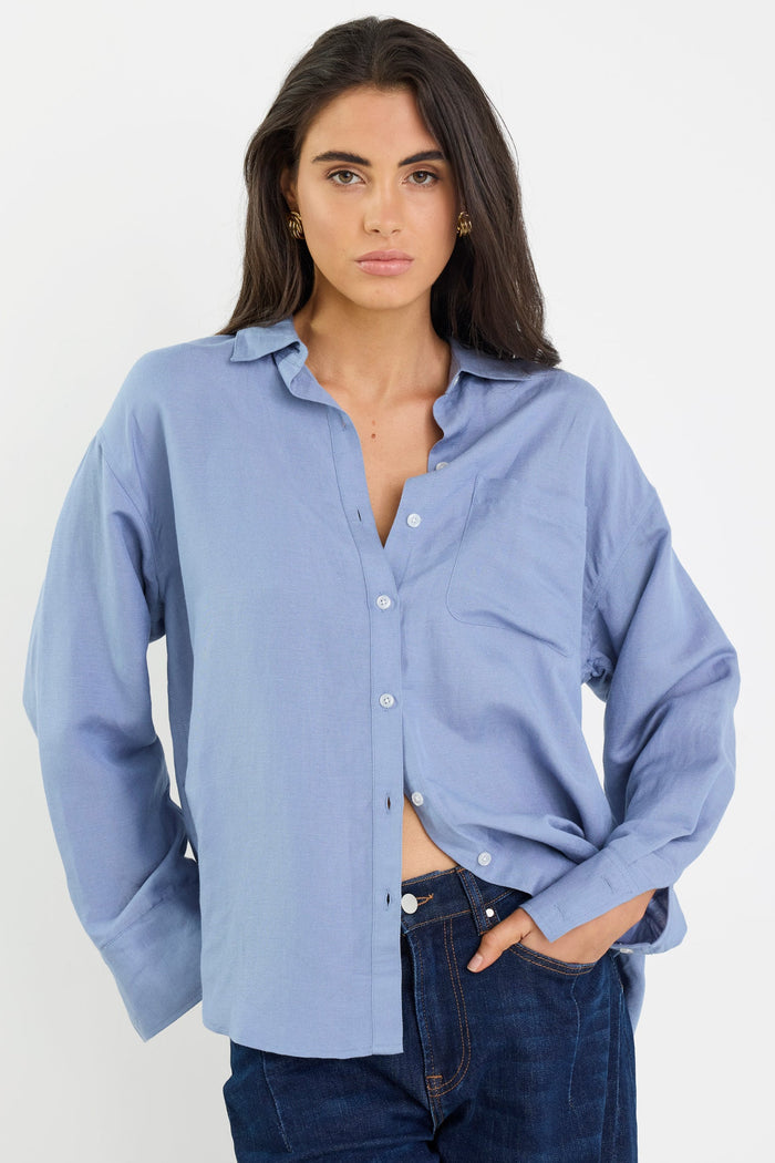 Woman wearing a light blue shirt and dark jeans on a white background