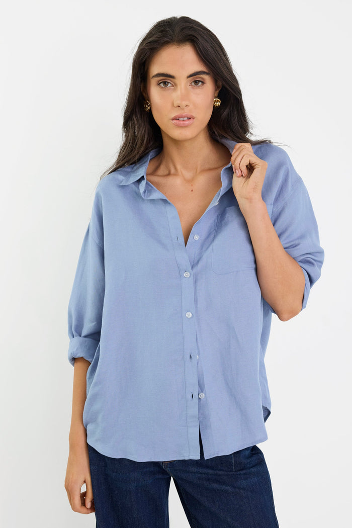 Woman wearing a light blue shirt and dark jeans on a white background