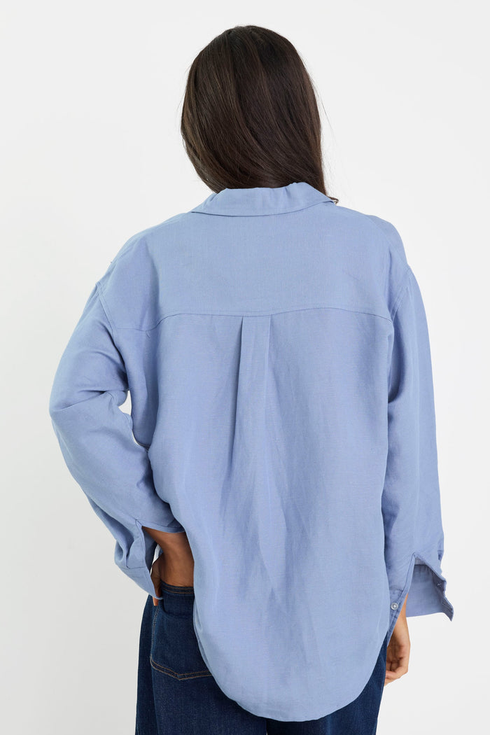 Person wearing a light blue shirt and dark jeans on a white background