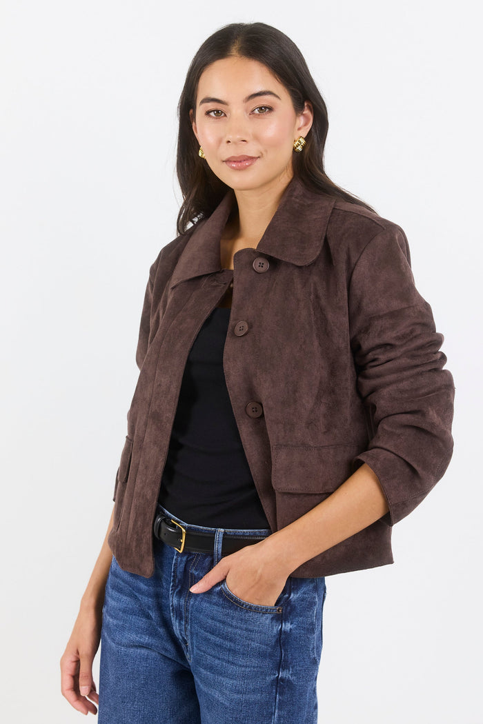 Woman wearing a brown jacket and blue jeans on a white background
