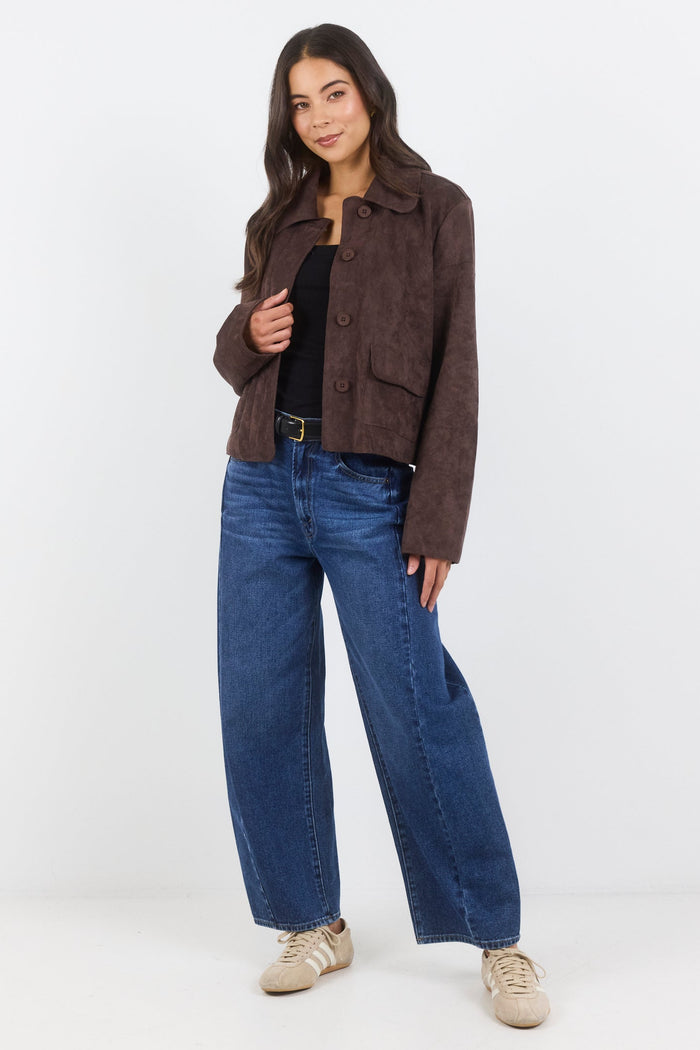 Woman wearing a brown jacket and blue jeans on a white background