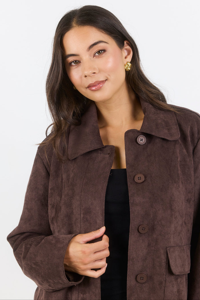 Woman wearing a brown coat against a white background