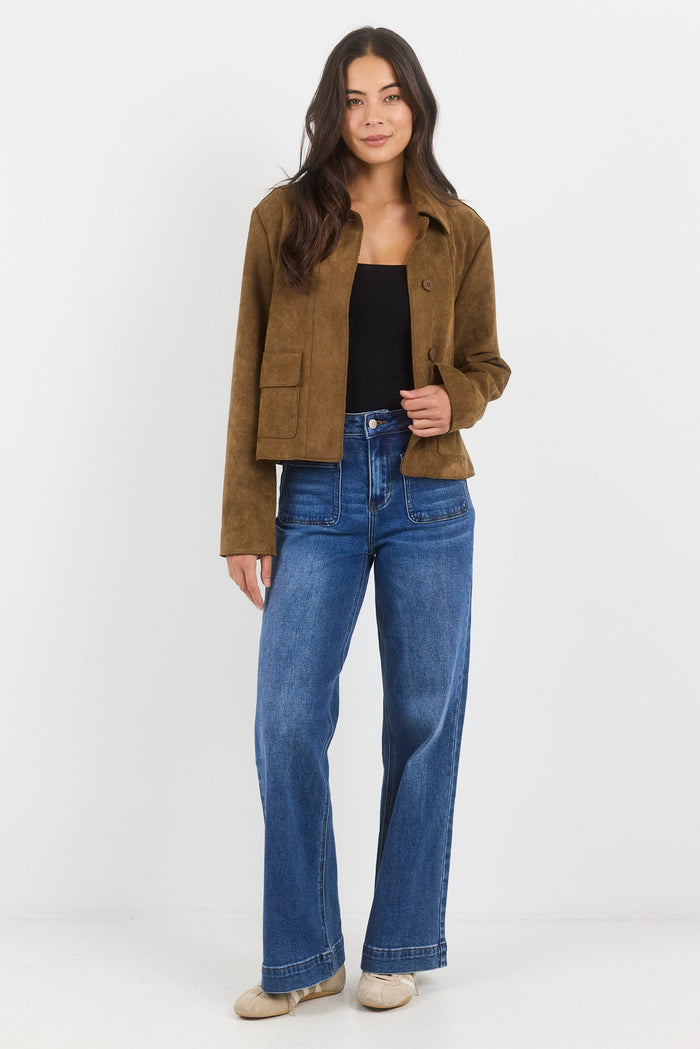 Woman wearing a brown jacket and blue jeans on a white background
