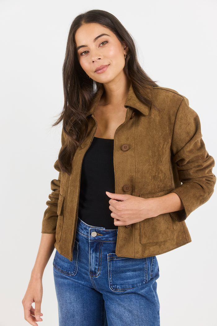 Woman wearing a brown jacket and blue jeans on a white background