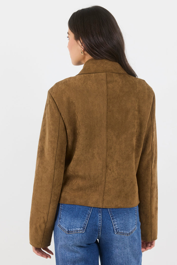 Person wearing a brown suede jacket and blue jeans on a white background