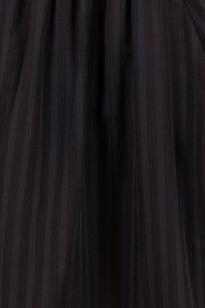 Close-up of a black pleated fabric garment, showing gathered texture and vertical pleats.