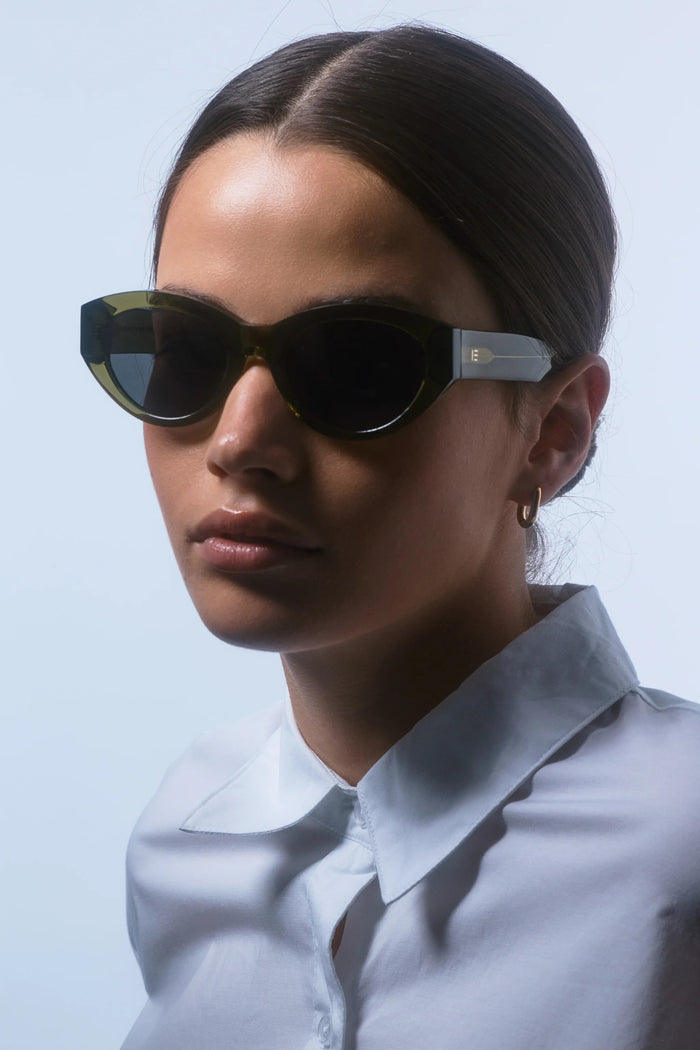 Woman wearing dark sunglasses against a light background