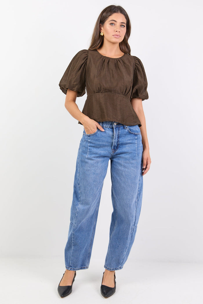 Woman wearing a brown top and blue jeans on a white background