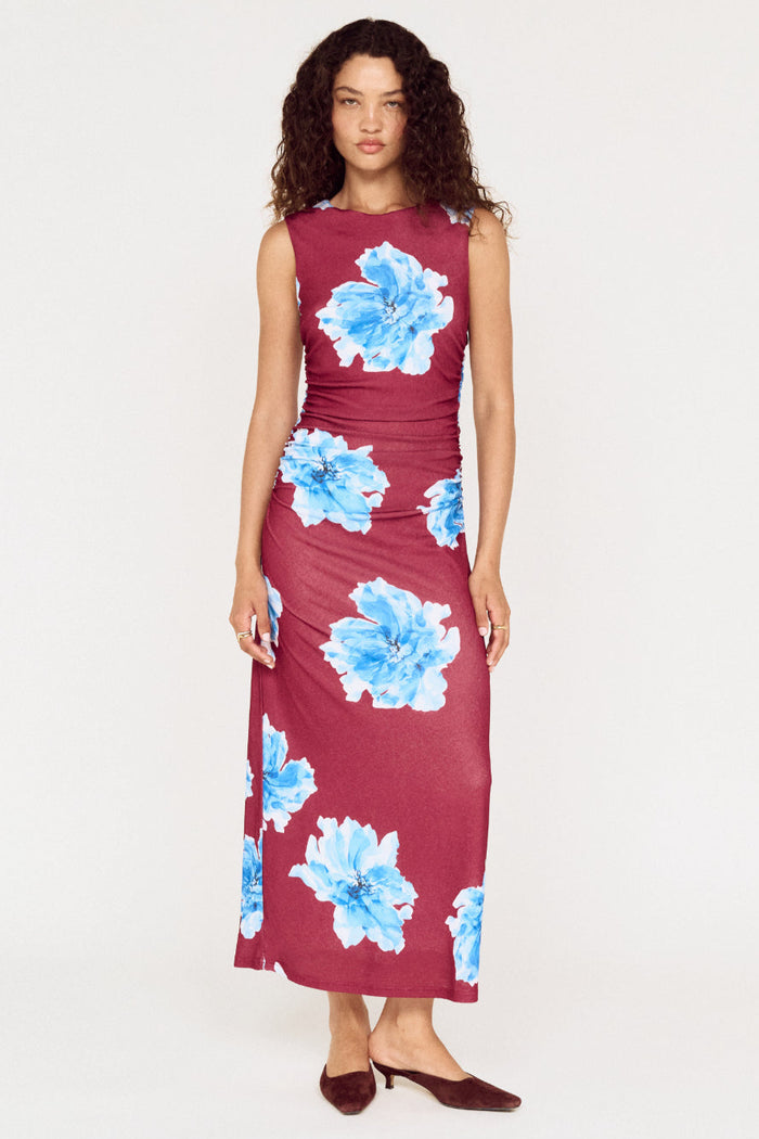 Woman wearing a burgundy dress with blue floral patterns on a white background