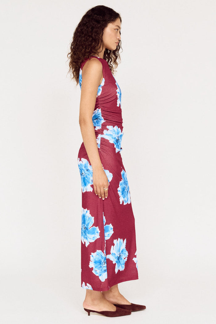 Woman wearing a burgundy dress with blue floral patterns on a white background