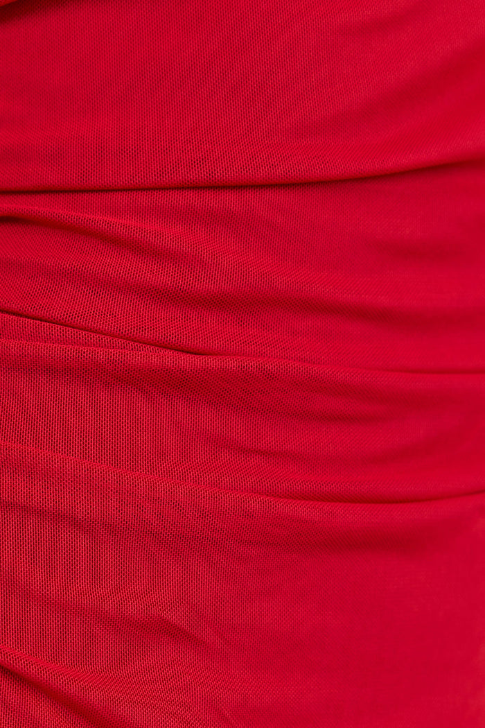 A close-up of draped red fabric with soft folds and a smooth texture.