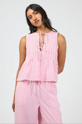 Woman wearing a pink and white striped sleeveless top and pants on a light gray background
