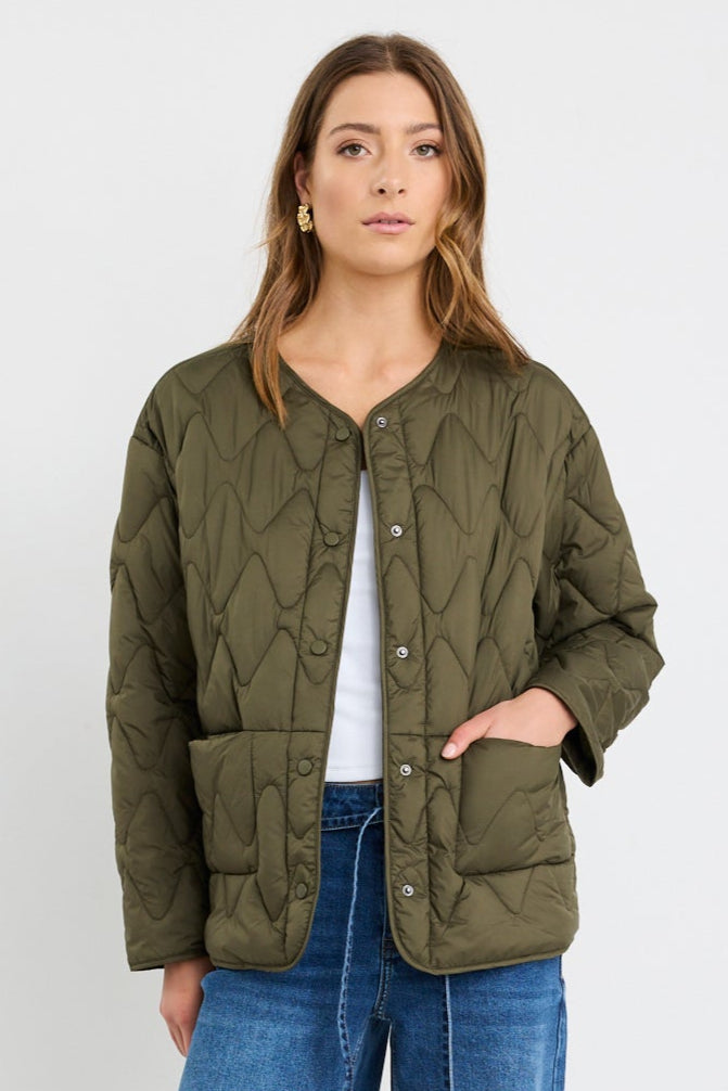 Woman wearing a green jacket and blue jeans on a white background