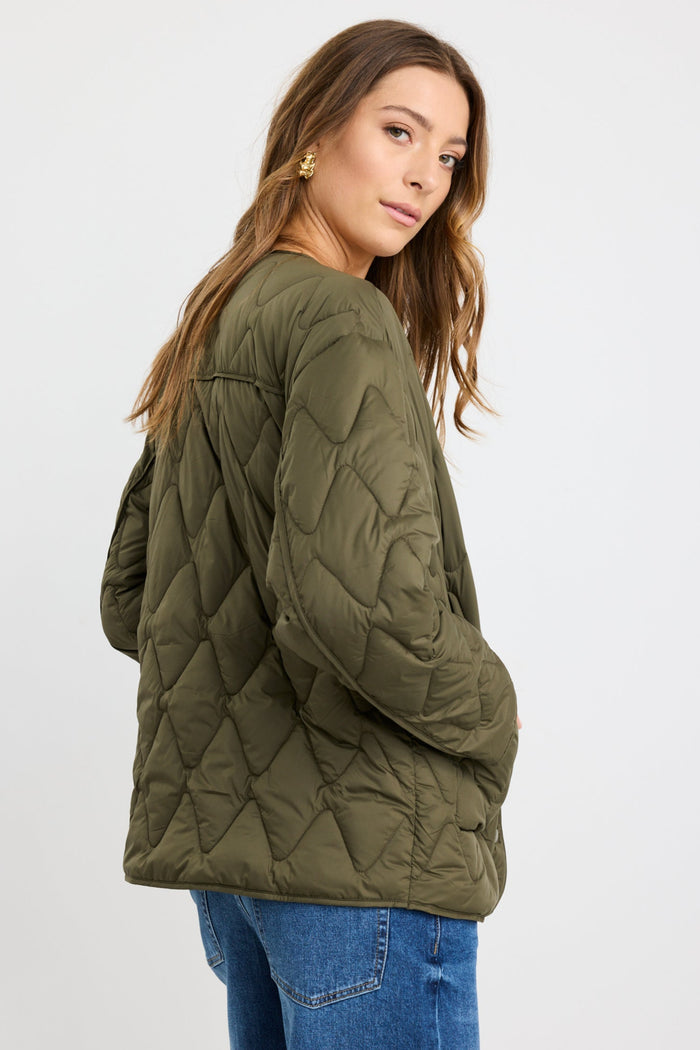 Woman wearing a green quilted jacket on a white background