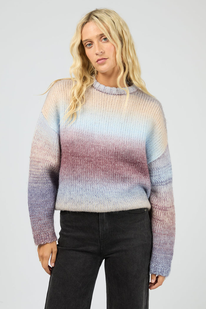 Woman wearing a multicolored sweater against a plain background