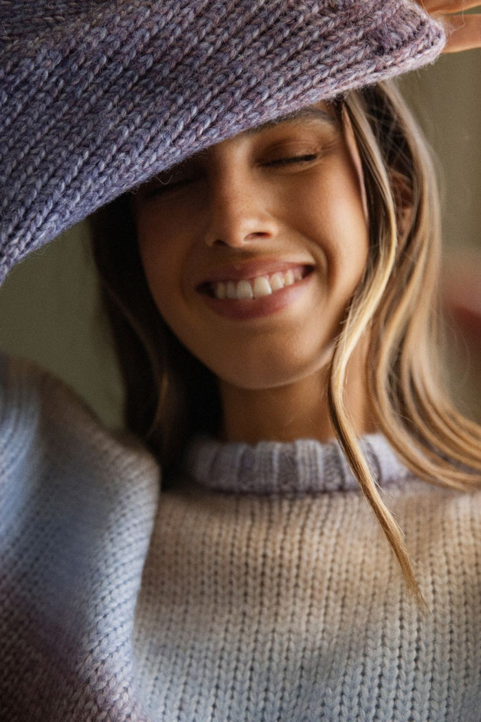 Woman wearing a knitted hat and sweater, smiling.