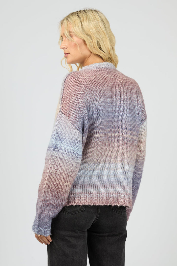 Woman wearing a multicolored knit sweater on a plain background