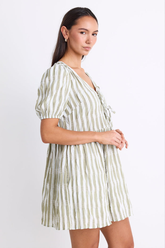 Model wearing a khaki striped puff sleeve mini dress with a V-neckline, puff sleeves, and a tie detail at the front.