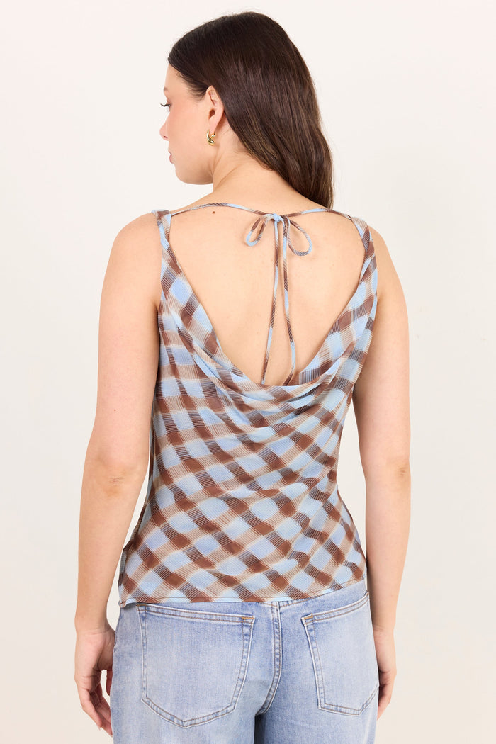 A woman shown from the back wearing a brown and light blue checkered tie-shoulder top and light-wash jeans, against a plain off-white studio background.