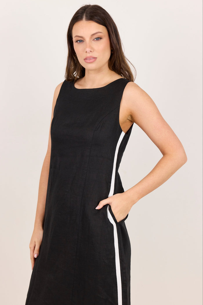 A woman modeling a sleeveless black dress with a white vertical stripe detail along the side, set against a plain light background.