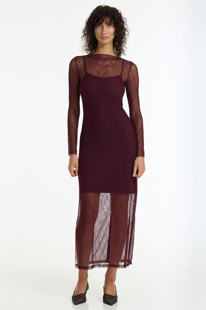 Woman wearing a burgundy dress with sheer sleeves on a white background