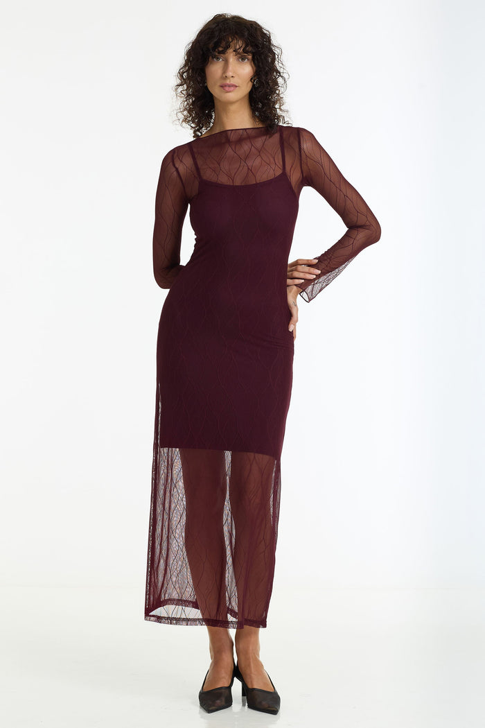 Woman wearing a burgundy dress with sheer sleeves and bottom half on a white background