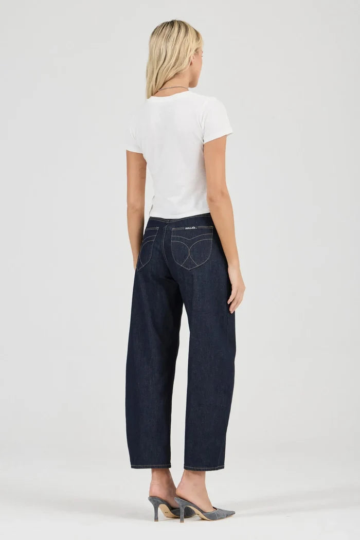 Woman wearing dark blue jeans and a white top on a light gray background