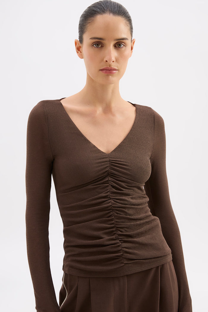 Woman wearing a brown long-sleeve top with a V-neck on a white background